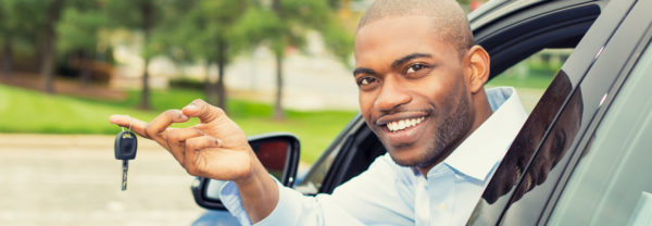 Smiling man dangling car keys from driver side window